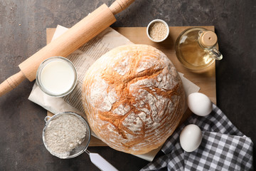 Tasty bread with ingredients for dough on grey background