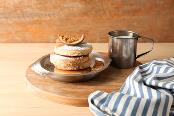 Tasty pancakes with passion fruit and mug of milk on table