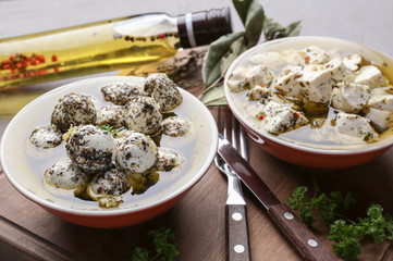 Bowls with tasty cheese and oil on table