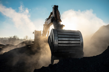 Yellow big excavator in the coal mine, loads the breed, with the bright sun and nice blue sky in the background. Mining truck mining machinery. Technique in coal mine © timofeev