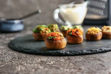 Slate plate with tasty stuffed mushrooms on grey table