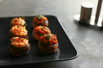 Plate with tasty stuffed mushrooms on grey table
