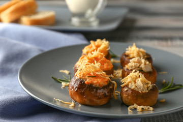 Plate with tasty stuffed mushrooms on table