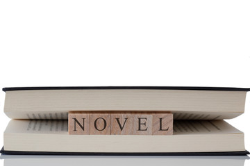 Novel written on wooden blocks inside a book isolated on a white background with reflection