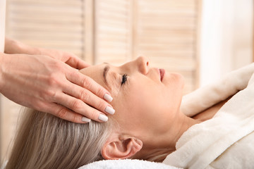 Fototapeta na wymiar Mature woman receiving face massage in beauty salon