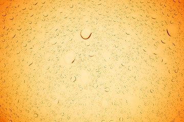 Rain droplets on yellow glass background, Water drops on yellow glass.