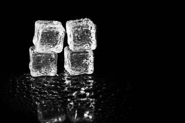 ice cubes reflection on black table background.