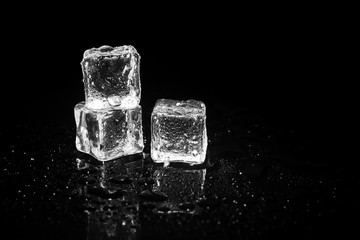 ice cubes reflection on black table background.