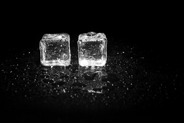 ice cubes reflection on black table background.