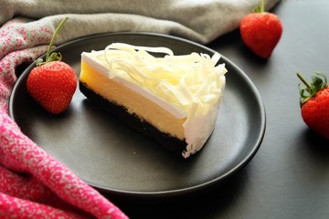 White chocolate cheesecake on black plate. 