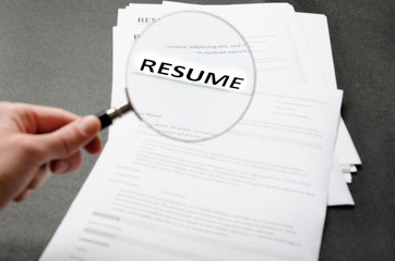 Recruiter`s workplace, pile of resume examples,hand holding magnifier,Concept of analyzing information about new employees