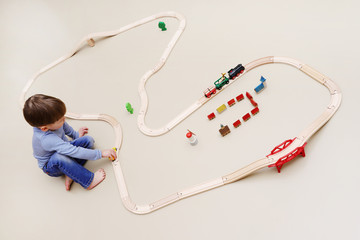 Ein kleiner Junge spielt mit einer Holzeisenbahn