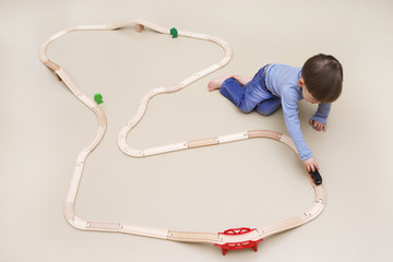 Ein kleiner Junge spielt mit einer Holzeisenbahn