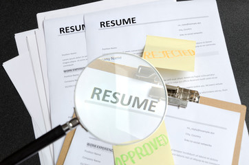 Pile of resume templates and sticks on it, black background. HR made decision and approved one...
