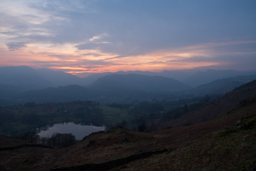 The Great Langdale sykline at sunset over Loughrigg Tarn seen from the slopes of Loughrigg Fell, Lake District, UK