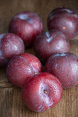 Top view of fresh plums on wooden background