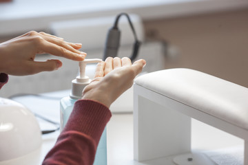 Woman desinfecting her hands before manicure procedure. Master preparing place for client. Hand...