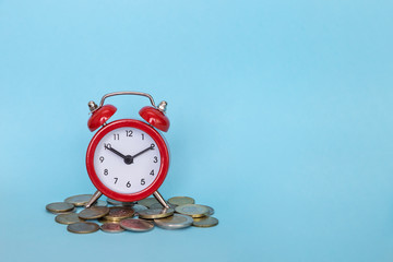 The alarm clock stands on a stack of money on a blue background