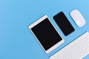 Smart phone, tablet, mouse and keyboard on sky blue background, flat lay