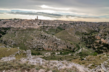 Fototapeta na wymiar Amazing panoramic wide view of ancient town of Matera, the Sassi di Matera, Basilicata, Southern Italy, cloudy summer afternoon just before sunset