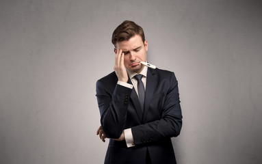 Young tired businessman with thermometer and copy space
