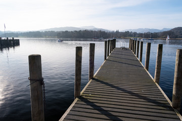 The pier at Ambleside Waterhead on a clear day looking over the Great Langdale skyline, Lake District, UK