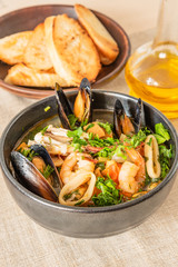 Homemade cioppino in a bowl and toast on a light rustic background - Italian-American seafood soup...