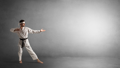 Small karate man fighting in an empty grey copy space