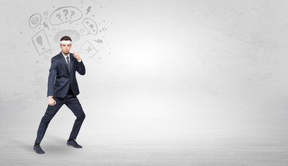 Young businessman in suit fighting with doodled symbols concept
