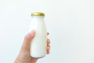 Woman hand holding a bottle of milk on white background.