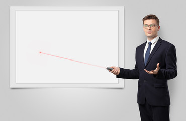 Young businessman with laser pointer and copyspace white blackboard
