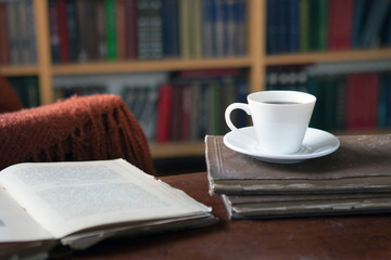 Sweet moments of relaxation with books and a cup of coffee. A man in an armchair with a cat. Vintage books, glasses, library. 