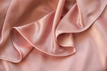Close up fabric. The silk fabric is laid out waves. Pink sateen fabric for background or texture.