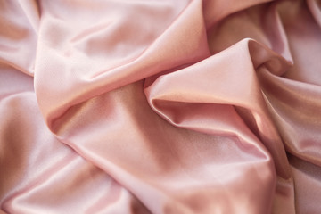 Close up fabric. The silk fabric is laid out waves. Pink sateen fabric for background or texture.