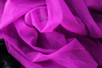 Close up pink fabric. The purple fabric is laid out waves. Fuchsia sateen fabric for background or texture.