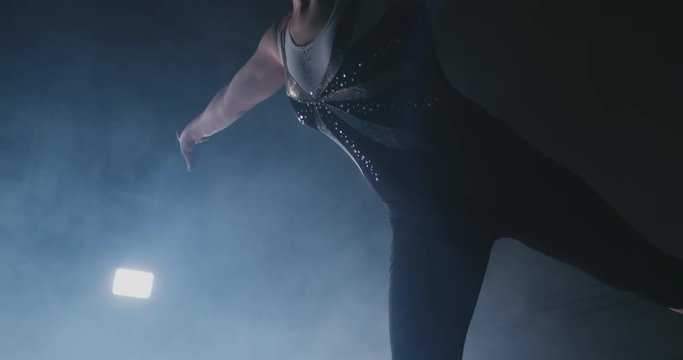 In slow motion in the smoke, a girl athlete stands with her arms raised after performing exercises. Welcome gesture with your hands.