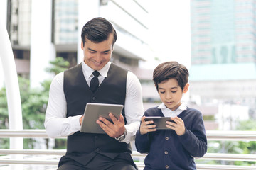 Obraz premium Father and son playing game smart phone together on business district urban, Dad and Son happy family concept