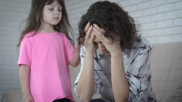Depressed woman. The mother is at a loss, her little daughter takes pity on her.