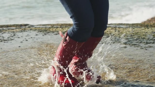 Happy Woman dancing, jumping on puddles On The Beach, Slow Motion. Woman enjoying the sun and feeling the freedom. 4K