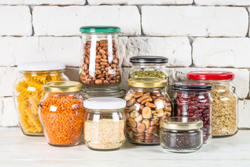 Fototapeta na wymiar Cereals, Legumes, and beans in glass jars on white kitchen table. 