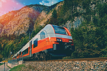 Red blue train in motion in Austrian alps mountains. High speed mountain train arrives at Hallstatt...