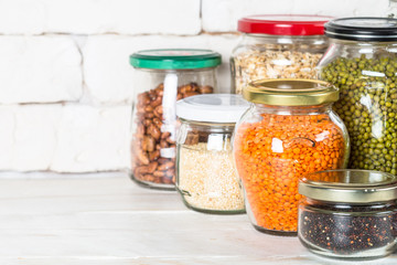 Cereals, Legumes, and beans in glass jars on white kitchen table. 