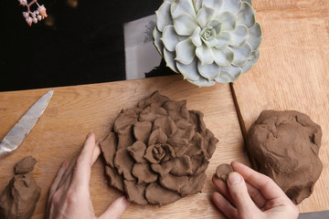 Closeup of hands sculpt clay plant decoration. Hands modeling crafts pottery. Sculpting clay in the...