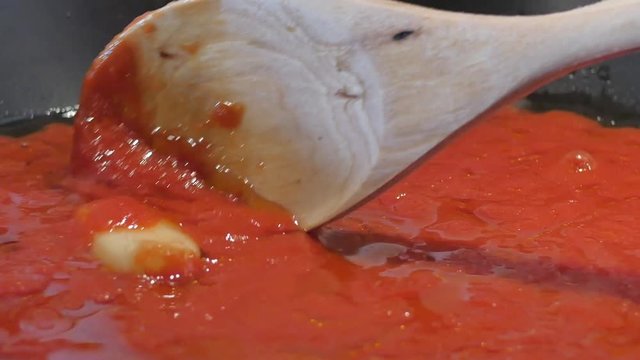 stir red tomato soup with wood tablespoon