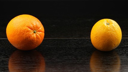 Two orange fruits on the black background