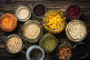 Cereals, Legumes, and beans in glass jars on  dark wooden table. 