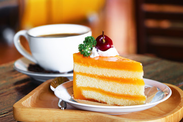Orange cake and a cup of hot coffee on wooden background..
