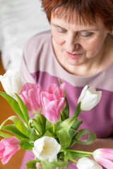 1 white adult woman with a bouquet of pink and white tulips