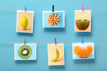 pictures with fruits hanging on a linen thread on stationery on clothespin on a colored background, concept of cheerful mood, design of home wall decor, photo frame, advertising of food business