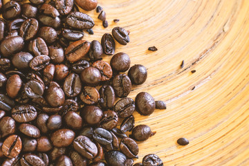 The coffee beans on wood plate close up image.